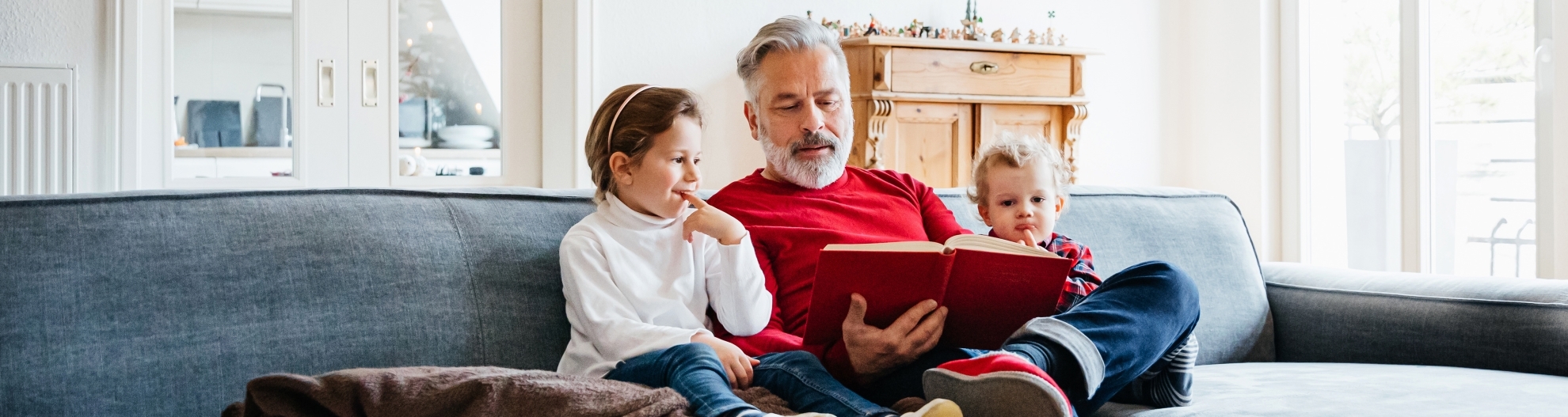 Grandfather reading to grandkids on the couch